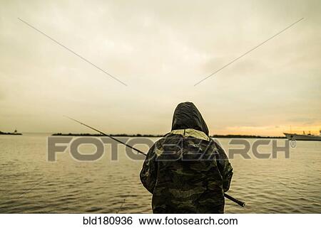 Stock Photograph - Caucasian man fishing in remote lake. Fotosearch