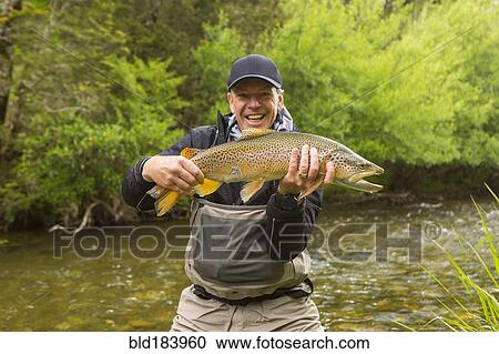 Caucasian man holding fish in remote river View Large Photo Image Stock Image - Caucasian man holding fish in remote river. Fotosearch