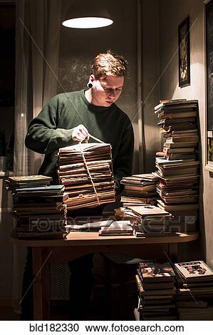 Stock Image - Caucasian man holding stack of books. Fotosearch