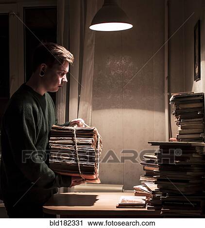 Stock Image - Caucasian man holding stack of books. Fotosearch