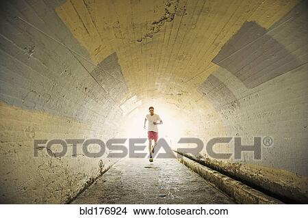 Picture - Caucasian man jogging in tunnel. Fotosearch