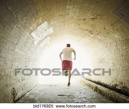 Stock Photography - Caucasian man jogging in tunnel. Fotosearch