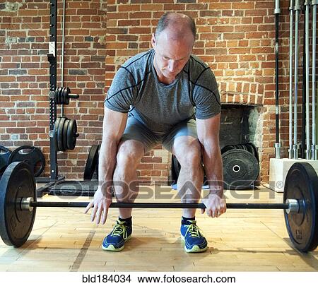 Picture - Caucasian man lifting weights in gymnasium. Fotosearch
