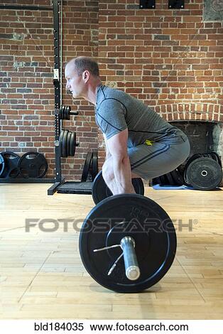 Stock Photography - Caucasian man lifting weights in gymnasium. Fotosearch