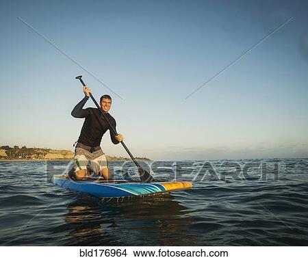 Picture - Caucasian man on paddle board in ocean. Fotosearch