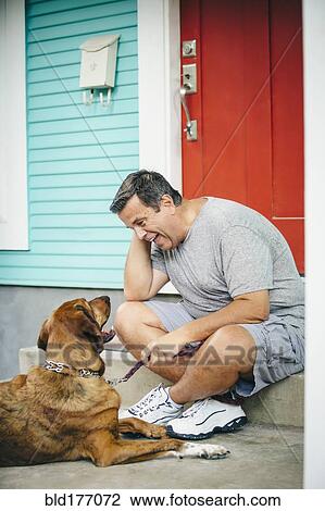 Caucasian man petting dog in front stoop View Large Photo Image Stock Image - Caucasian man petting dog in front stoop. Fotosearch