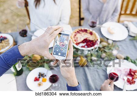 Caucasian man photographing food at outdoor table View Large Photo Image Picture - Caucasian man photographing food at outdoor table. Fotosearch