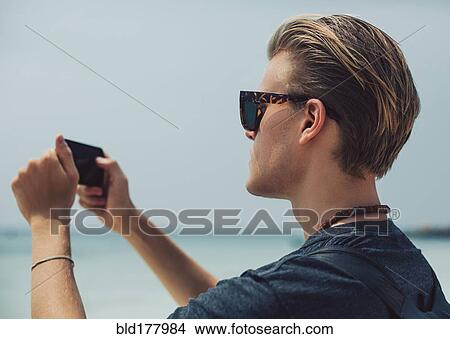 Picture - Caucasian man photographing seascape. Fotosearch