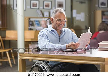 Stock Photograph - Caucasian man reading in library. Fotosearch
