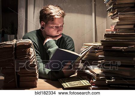 Caucasian man reading stack of books View Large Photo Image Picture - Caucasian man reading stack of books. Fotosearch