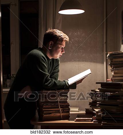 Stock Image - Caucasian man reading stack of books. Fotosearch