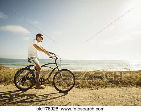 Caucasian man riding bicycle on beach View Large Photo Image Stock Photo - Caucasian man riding bicycle on beach. Fotosearch