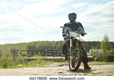 Stock Image - Caucasian man riding dirt bike in field. Fotosearch