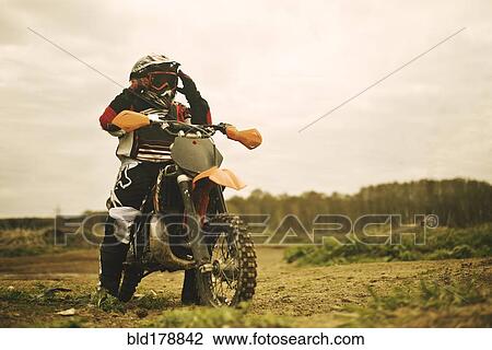 Stock Image - Caucasian man riding dirt bike in field. Fotosearch