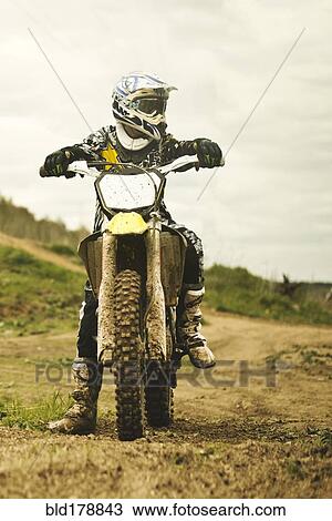 Stock Image - Caucasian man riding dirt bike in field. Fotosearch