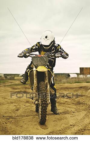 Stock Photo - Caucasian man riding dirt bike in field. Fotosearch