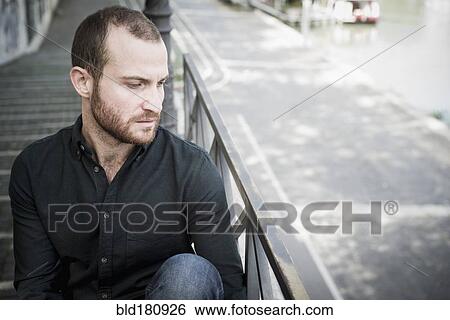 Stock Photograph - Caucasian man sitting on outdoor staircase. Fotosearch