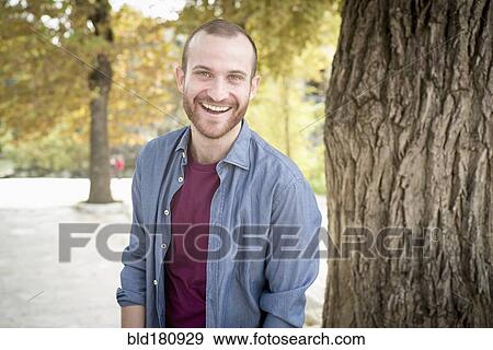 Caucasian man smiling in park View Large Photo Image Stock Photo - Caucasian man smiling in park. Fotosearch