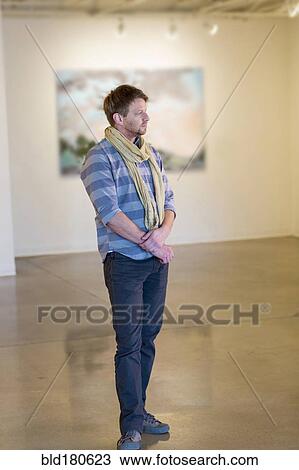 Stock Image - Caucasian man standing in art gallery. Fotosearch