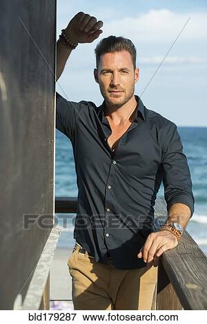 Stock Photo - Caucasian man standing on beach pier. Fotosearch