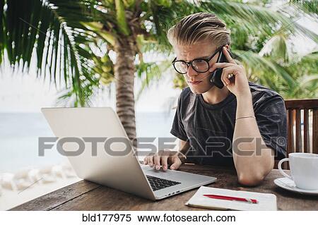 Stock Photography - Caucasian man talking on cell phone in cafe. Fotosearch