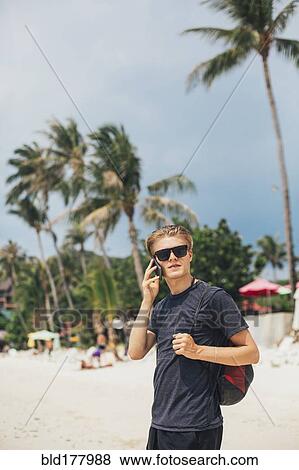 Stock Photo - Caucasian man talking on cell phone on beach. Fotosearch