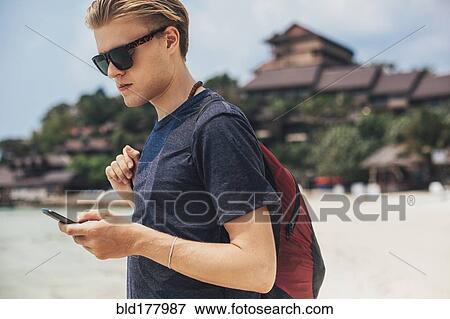 Caucasian man using cell phone on beach View Large Photo Image Stock Photo - Caucasian man using cell phone on beach. Fotosearch