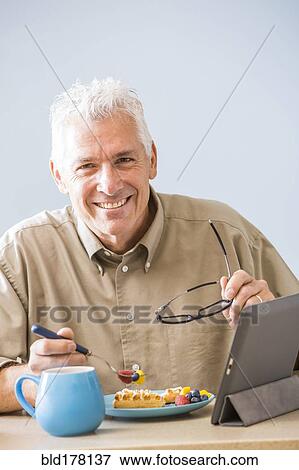 Stock Photo - Caucasian man using digital tablet at table. Fotosearch