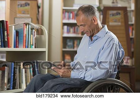 Caucasian man using digital tablet in library View Large Photo Image Picture - Caucasian man using digital tablet in library. Fotosearch