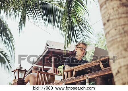 Stock Image - Caucasian man using laptop in cafe. Fotosearch