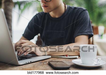 Stock Photo - Caucasian man using laptop in cafe. Fotosearch