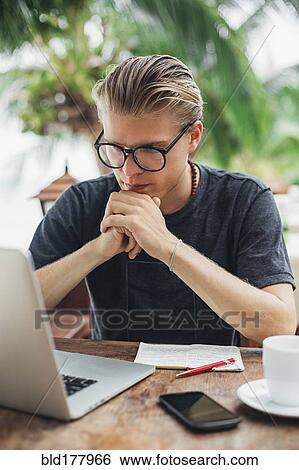 Stock Photograph - Caucasian man using laptop in cafe. Fotosearch