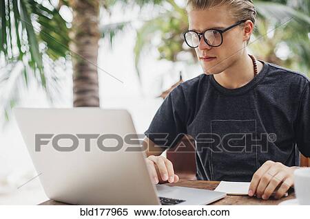 Stock Photography - Caucasian man using laptop in cafe. Fotosearch