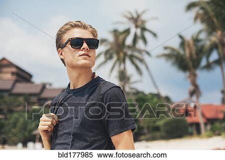 Stock Photography - Caucasian man walking on beach. Fotosearch