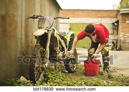 Stock Photo - Caucasian man washing dirt bike. Fotosearch