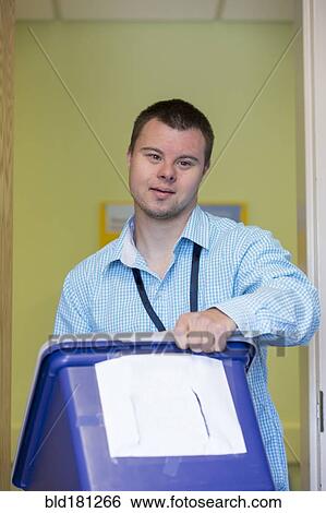 Caucasian man with Down Syndrome carrying bin in office View Large Photo Image Stock Photograph - Caucasian man with Down Syndrome carrying bin in office. Fotosearch