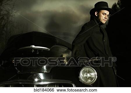 Stock Photograph - Caucasian man working on broken-down vintage car. Fotosearch