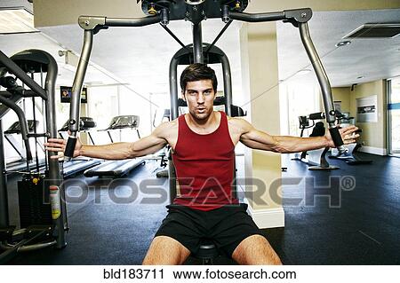 Stock Image - Caucasian man working out in gymnasium. Fotosearch