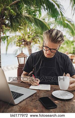 Stock Image - Caucasian man writing in cafe. Fotosearch