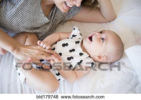 Caucasian mother and baby daughter laying on bed View Large Photo Image Stock Photo - Caucasian mother and baby daughter laying on bed. Fotosearch