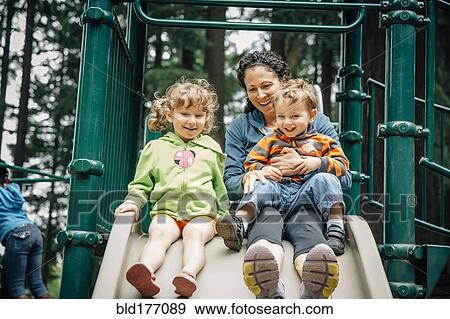 Stock Photo - Caucasian mother and children playing on playground. Fotosearch