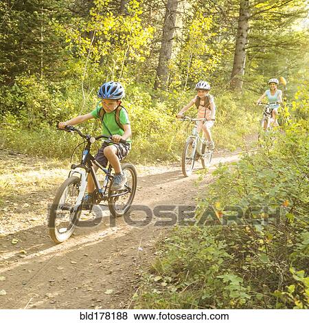 Stock Photo - Caucasian mother and children riding mountain bikes. Fotosearch
