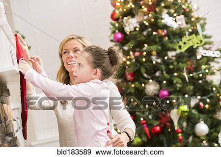 Caucasian mother and daughter hanging Christmas stockings View Large Photo Image Stock Photo - Caucasian mother and daughter hanging Christmas stockings. Fotosearch