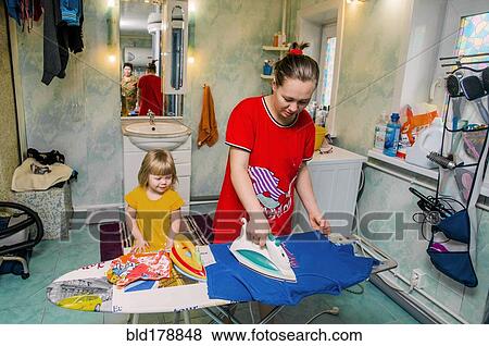Stock Photo - Caucasian mother and daughter ironing laundry. Fotosearch