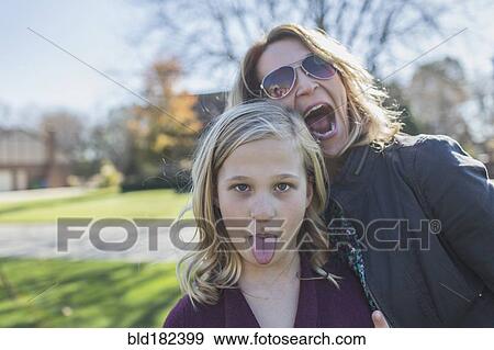 Stock Photo - Caucasian mother and daughter making faces outdoors. Fotosearch