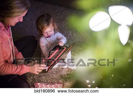 Stock Photograph - Caucasian mother and daughter opening Christmas gift. Fotosearch
