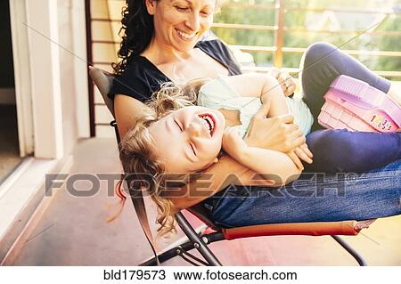 Stock Image - Caucasian mother and daughter playing on patio. Fotosearch