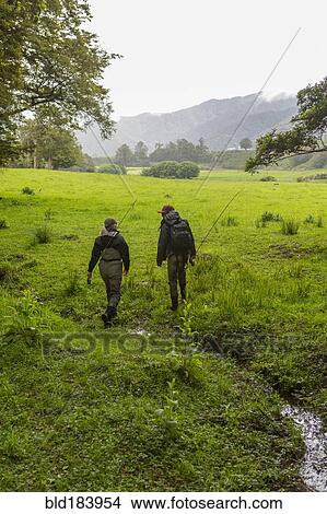 Picture - Caucasian mother and daughter walking in remote field. Fotosearch