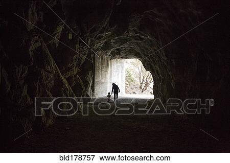 Stock Photo - Caucasian mother and daughter walking in cave. Fotosearch