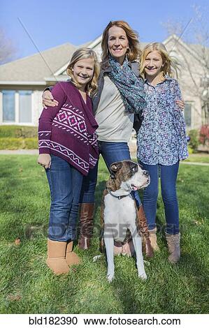 Stock Image - Caucasian mother and daughters smiling with dog. Fotosearch